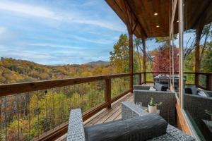 加特林堡The Overlook - '21 Cabin - Gorgeous Unobstructed Views - Fire Pit Table - GameRm - HotTub - Xbox - Lots of Bears的一个带椅子并享有树林美景的阳台