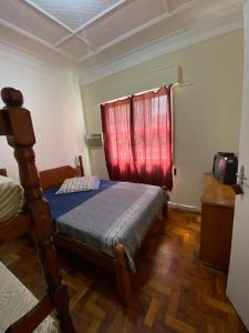 桑托斯Pousada J.C. Cazeri的一间卧室设有一张床和一个红色的窗户