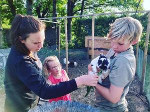 HarelbekeDe Skure: vakantiewoning op boerderij的两个孩子和一个抱着小山羊的女人