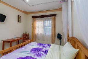 恩德培Airport Side Hotel Entebbe的一间卧室配有一张带紫色床单的床和窗户。