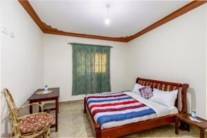 恩德培Airport Side Hotel Entebbe的卧室配有床、椅子和窗户。