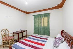 恩德培Airport Side Hotel Entebbe的一间卧室配有一张床、一张桌子和一个窗户。