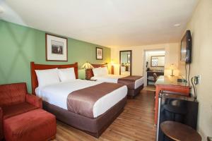 梅肯Travelodge by Wyndham Macon West的酒店客房,配有两张床和椅子