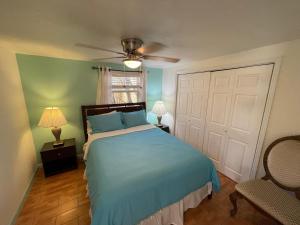 西棕榈滩4BR Downtown House Near Beach, Pet Friendly的一间卧室配有蓝色的床和吊扇