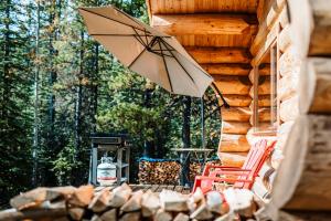 Rock Lake Lodge Provincial ParkRocky Mountain Escape Log Cabin Rentals - Rock Lake的庭院配有桌椅和遮阳伞。