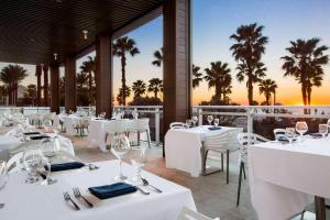 克利尔沃特大克利尔沃特海滩温德姆至尊酒店的餐厅拥有白色的桌椅和棕榈树