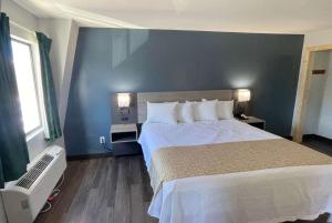 鸽子谷Travelodge by Wyndham Pigeon Forge Dollywood Lane的一间卧室设有一张大床和蓝色的墙壁
