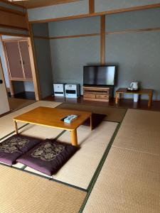 高山山水民宿的客厅配有桌子和电视