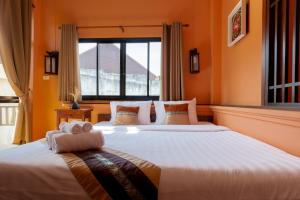 清迈清迈萱格旅馆的橙色墙壁和窗户的客房内的两张床