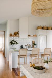 丹马克Upland Farm Luxury Cabins, Denmark Western Australia的厨房配有白色橱柜和桌椅