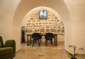 耶路撒冷Cozy Heritage Home Jerusalem的一间设有石墙和桌椅的用餐室