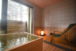 驹根市山吹旅馆的客房设有热水浴缸、椅子和窗户。