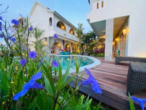 坎古MAHALONA BALI STAY的一座带游泳池和紫色鲜花的房子