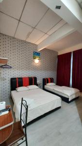 马六甲Hotel Bestari的客房设有两张床、一张桌子和一张书桌。