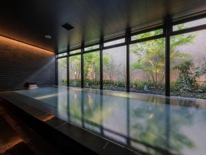 熊本THE BLOSSOM KUMAMOTO的一座带窗户的建筑中的游泳池