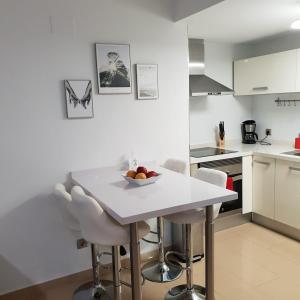 阿利坎特Apartamento con vistas al mar的白色的厨房配有白色的桌子和椅子