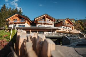 安达洛La Dila Dolomiti Mountain Lodge的一座大型木屋,前面设有围栏
