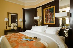 奥兰Royal Hotel Oran - MGallery Hotel Collection的一间卧室配有一张带书籍和绘画的床