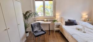 梅拉诺Bergblick Apartment in Zentrumsnähe mit Garage的一间卧室配有一张床、一张桌子、一张床和一个窗户。