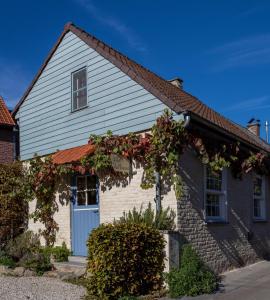 Zottegem米勒度假屋的白色的房子,有蓝色的门和鲜花