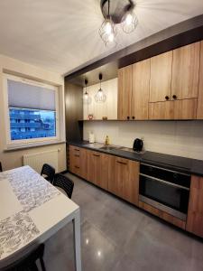 比亚韦斯托克Apartamenty Homely - Nowowarszawska 130的厨房配有木制橱柜、桌子和窗户。