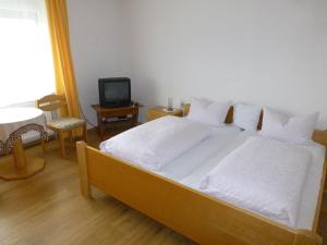 瓦尔德明兴Landgasthof "Altes Haus"的一间卧室配有一张带白色床单的床和电视。