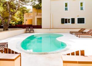 埃斯卡洛Apartamentos El Pino - Formentera Break的一座带椅子的游泳池以及一座建筑