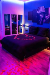 科尔贝埃索讷BLUE NIGHT - Jacuzzi - Bord de Seine的一间卧室配有一张黑色床和紫色灯