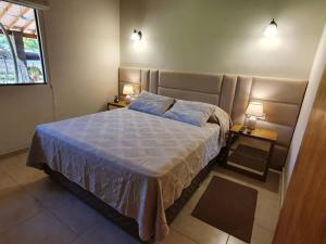 圣贝纳迪诺Casa con Piscina, Quincho, Cancha de Futbol/Volley的一间卧室配有一张带2个床头柜的大床