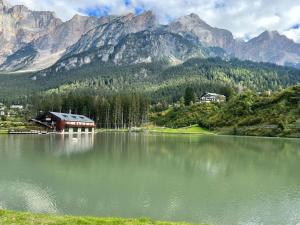 圣维托-迪卡多雷Mansarda su due livelli nel cuore delle Dolomiti的一座湖,有房子,有山,有背景