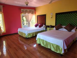 PerquínHotel y Restaurante Las Margaritas的红色和黄色墙壁的客房内的两张床