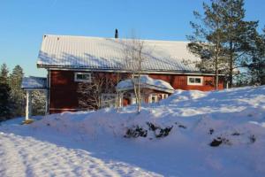 BäckeforsLillesjö stuguthyrning的前面的红谷仓,地上有雪