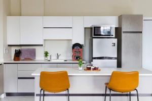 金斯敦Suite Retreat at The Lofts的厨房配有白色橱柜和2把橙色椅子