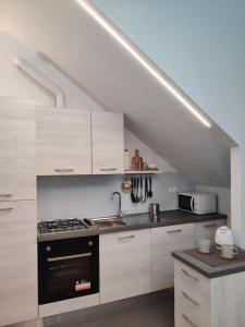卡托利卡Soggiorno a 5 stelle, tra mare, cultura e natura的厨房配有白色橱柜和黑炉灶烤箱。