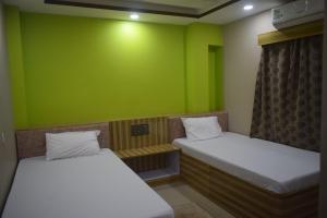 西里古里Airport Lodge的绿墙客房的两张床