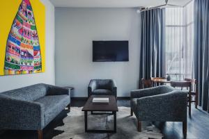 拉巴斯阿提克斯酒店的客厅配有两把椅子和电视