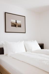 蒂鲁罗Culinaria living的一张铺有白色床单的床和一张墙上的照片