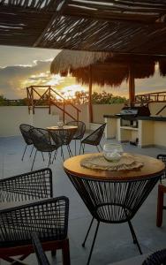 图卢姆Naajal Tulum Boutique Hotel - Magic & Jungle的露台配有桌椅,享有日落美景。