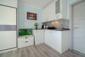 埃斯托利尔Gold Coast Photography Inn的厨房配有白色橱柜和平面电视。