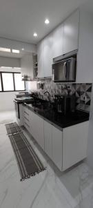 瓜鲁雅Apartamento Guarujá Astúrias的厨房配有白色橱柜和黑色台面