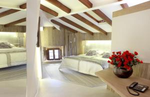普韦布拉桑纳比亚特莱科萨斯酒店的一间卧室设有两张床,一张桌子上放着花瓶