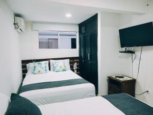 圣玛尔塔Hotel Tranvia的一间卧室配有两张床和一台平面电视