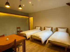 松本cafe&stay CASTANA的酒店客房设有两张床和一张桌子。
