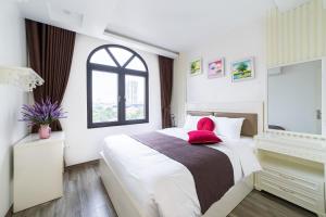 河内Rosee Apartment Hotel - Luxury Apartments in Cau Giay , Ha Noi的一间卧室配有一张带红色枕头的大床
