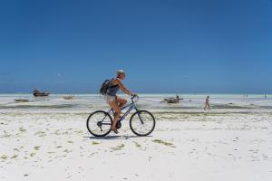 江比阿Jambo Jambiani Beach Villa, Beautiful private villa at 2 minutes from the Beach的一名妇女在海滩上骑着自行车