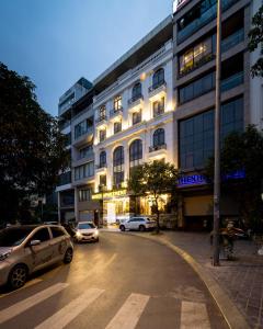 河内Rosee Apartment Hotel - Luxury Apartments in Cau Giay , Ha Noi的街道前有车辆停放的建筑物