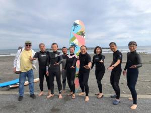 Ichinomiyaオーシャニア一宮的一群人站在海滩上,并带有冲浪板