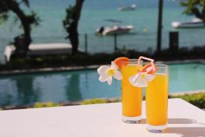 托舵道斯Valmarin Seafront Apartments的两杯橙汁坐在泳池旁的桌子上
