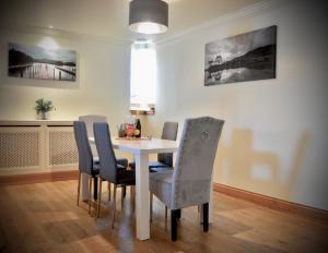 卢斯Lomond Castle Penthouse的一间配备有白色桌椅的用餐室