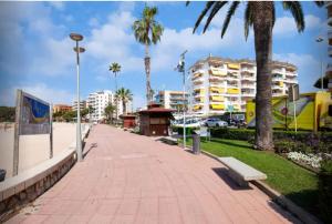 罗列特海岸One Bedroom Flat in Fenals Lloret de Mar for 4 People的一条拥有长凳、棕榈树和建筑的路边